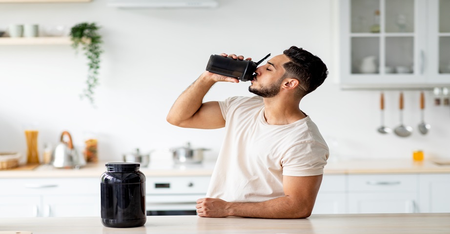 Mężczyzna pije odżywkę białkową na redukcji