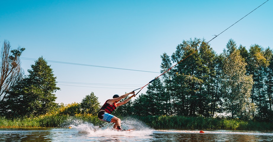 Mężczyzna uprawia sport wodny jakim jest wakeboarding.